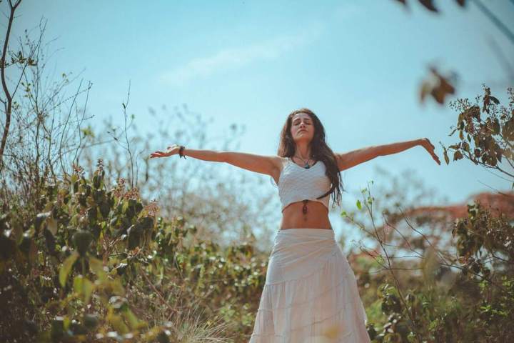 woman wearing white outfit arms wide open in a field of plants