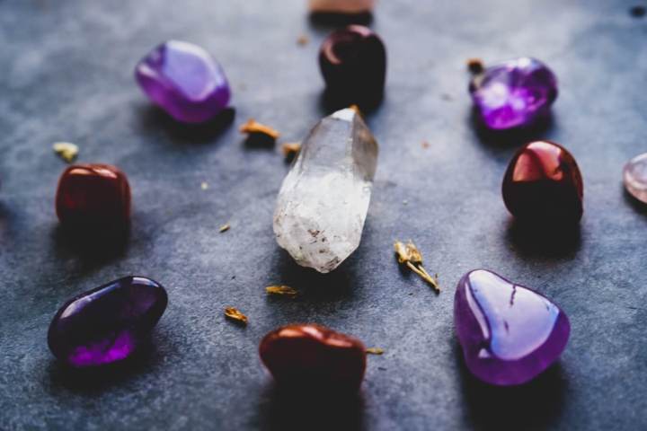 red and purple smooth stones arranged in a circles with a white crystal in the center