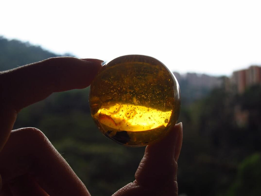 a hand holding an amber crystal